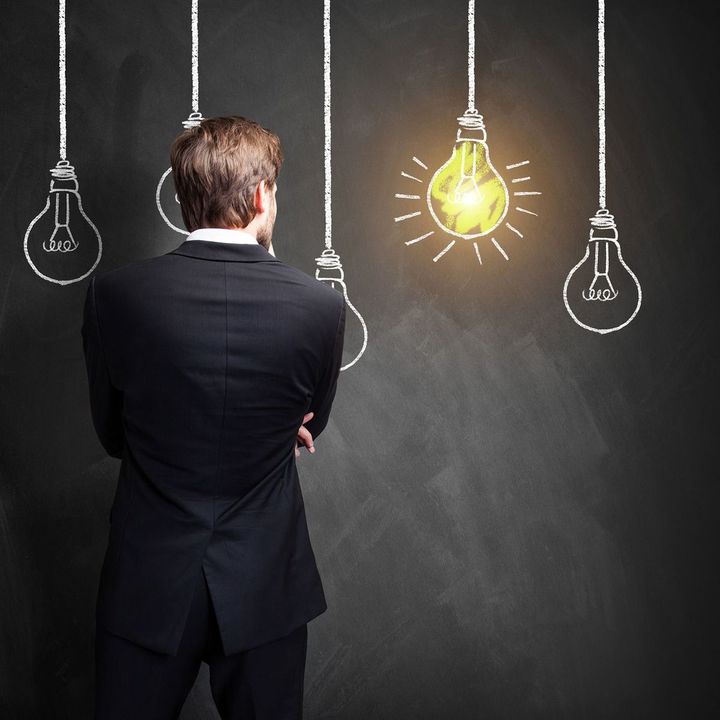 電球が描かれた黒板の前に立つ男性