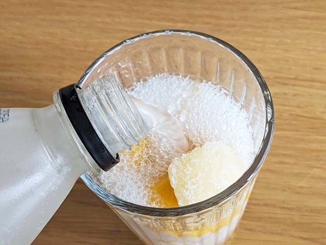 「ドール 完熟マンゴー」と「ドール 白桃」が入ったグラスに「サントリー天然水 特製レモンスカッシュ」を注いでいる様子