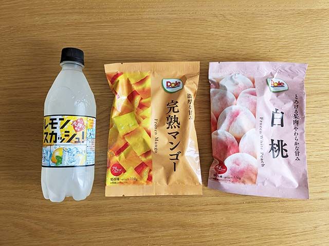 ファミリーマートで購入した「サントリー天然水 特製レモンスカッシュ 500mlペット」「ドール 完熟マンゴー」「ドール 白桃」がテーブルに置かれている様子