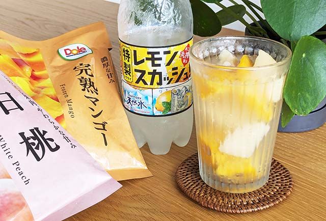 ファミリーマートで購入した「サントリー天然水 特製レモンスカッシュ 500mlペット」「ドール 完熟マンゴー」「ドール 白桃」とその材料で作ったアレンジドリンクがテーブルに置かれている様子