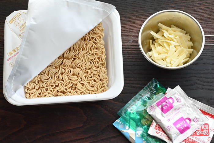テーブルの上に置かれたカップやきそばとシェラカップに入ったチーズの様子