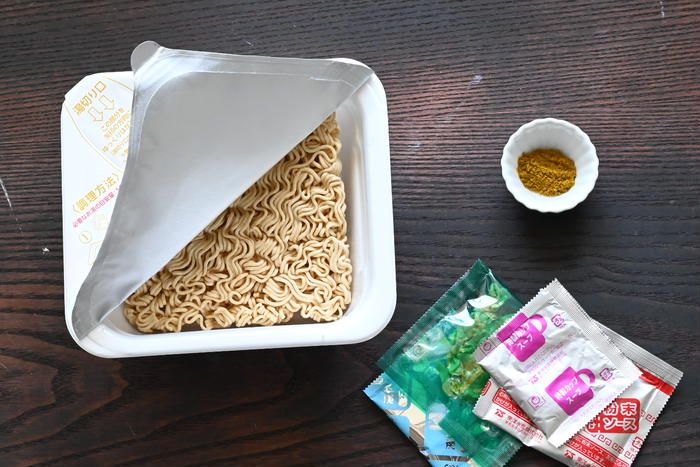 テーブルの上に置かれたカップやきそばとカレーパウダー