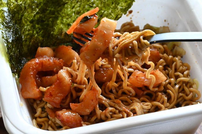 ファークで箸上げされたキムチ入りのカップ焼きそば