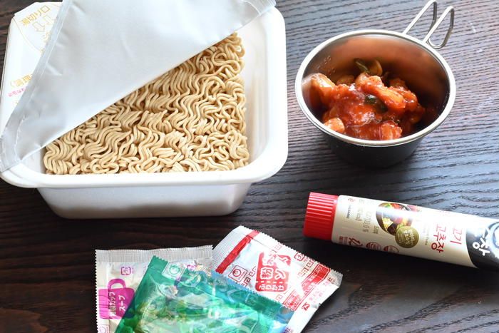 テーブルの上に置かれたカップ焼きそばとキムチ、チューブに入ったコチュジャン