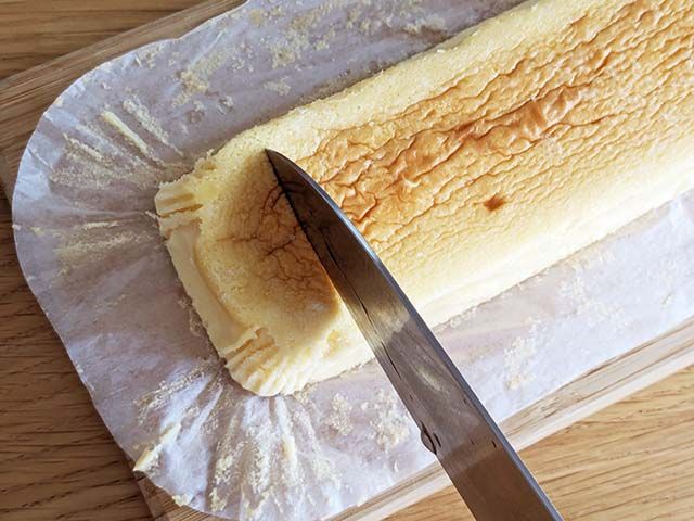 パッケージから出された業務スーパー「スフレチーズケーキ」を包丁でカットしている様子