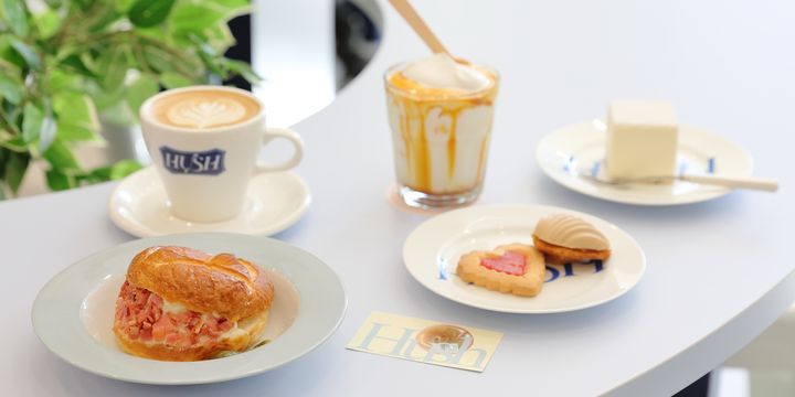 左手前から時計回りに「マッシュポテトベーコンベーグル」935円（テイクアウト918円）、「バニララテ」660円（テイクアウト648円）、「キャラメルビエンナ」715円（テイクアウト756円）、「スクエアチーズケーキ」858円(テイクアウト842円）、「ストロベリージャムクッキー」440円（テイクアウト432円）、「マドレーヌ（アップルキャラメル）」440円（テイクアウト432円）