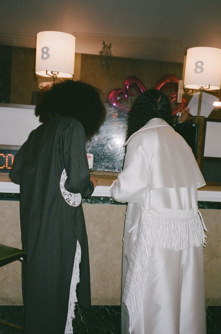 Image may contain_ Lighting, Lamp, Adult, Person, Clothing, Dress, Fashion, Formal Wear, Gown, Table Lamp, Cross, and Symbol