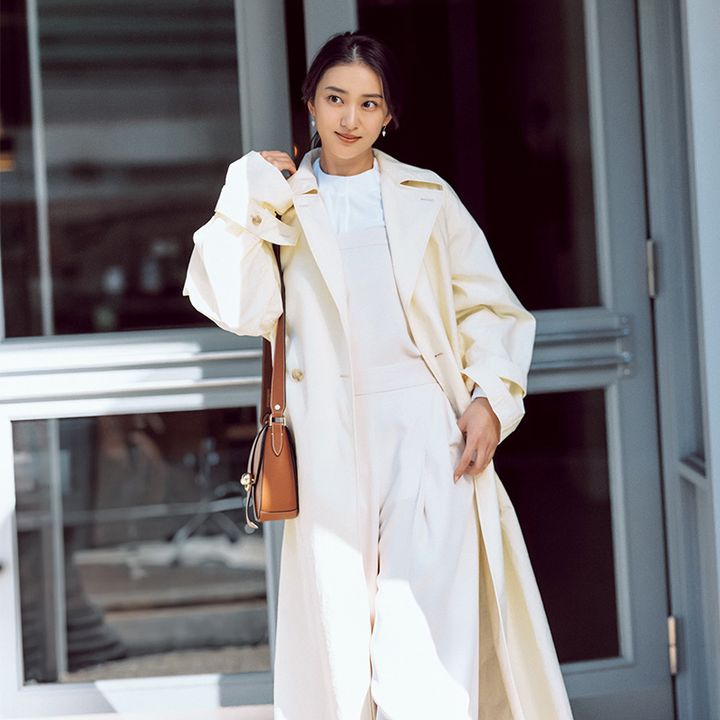 最高気温20度の服装例：白のオールインワンに淡いイエローのトレンチを羽織って好印象