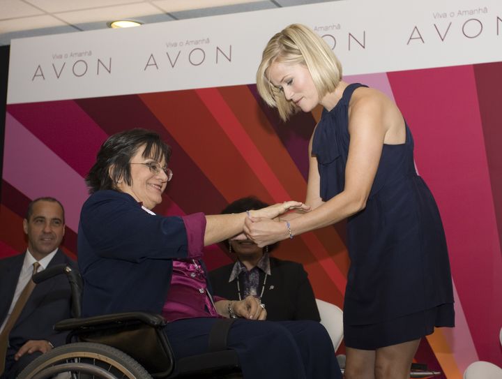 SAO PAULO, BRAZIL - AUGUST 28_ Avon Global Ambassador, Reese Witherspoon, puts the Women's Empowerment bracelet on Maria da Penha Maia Fernandes, who pioneered the fight against domestic violence in Brazil and inspired the creation of the Maria da Penha Act, during a press conference to spread messages of female empowerment and announce efforts to help reduce domestic violence in Latin America. (Photo By Marcos Jose Issa De Souza/Avon via Wireimage.com)