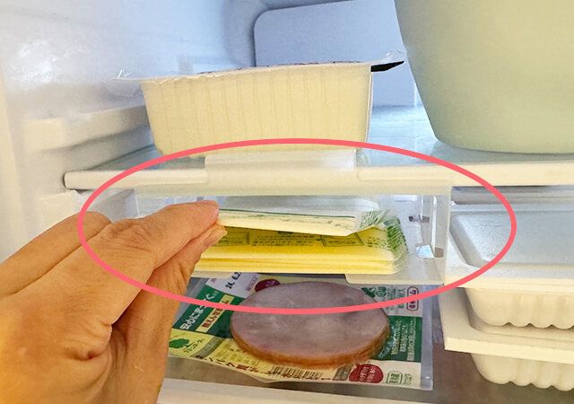 ダイソーの棚下食品収納ボックスからスライスチーズを取り出す