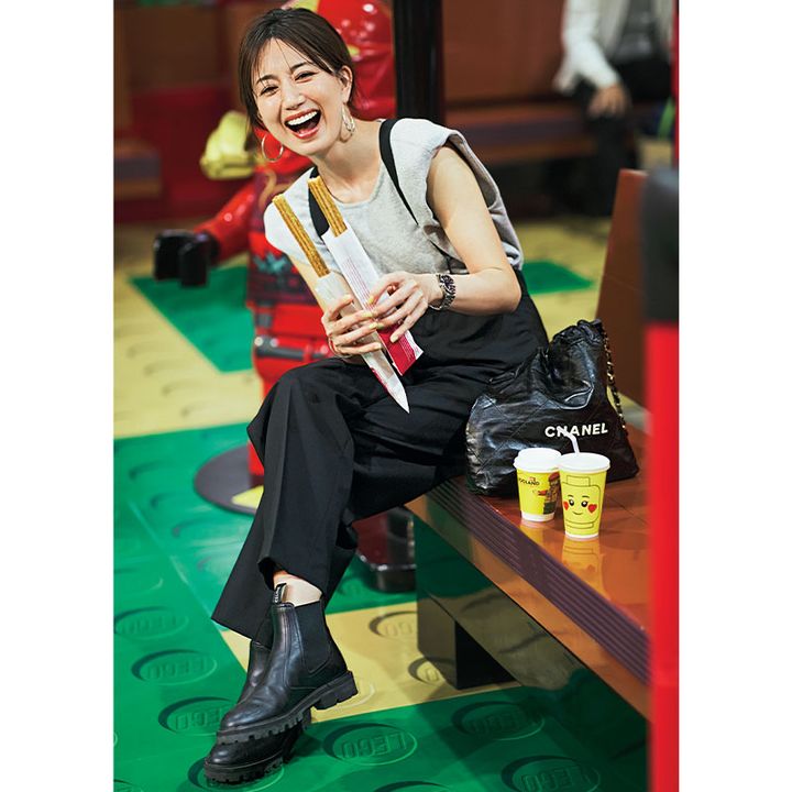 グレーのトップスと黒のサスペンダーパンツ、足元は黒ブーツを合わせた東原亜希さん