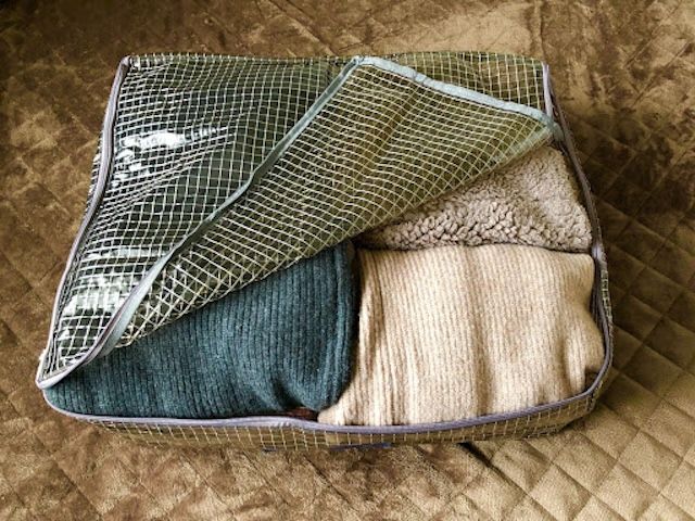 蓋つき収納に冬物衣類を入れて半分蓋を開けた様子