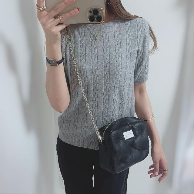 グレーのケーブルクルーネックセーターを着用している