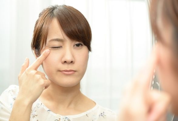 鏡でまつげを確認する女性