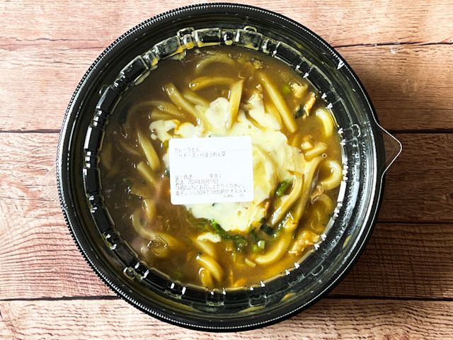テイクアウトの器に入った「ハーフチーズ・ハーフほうれん草カレーうどん」