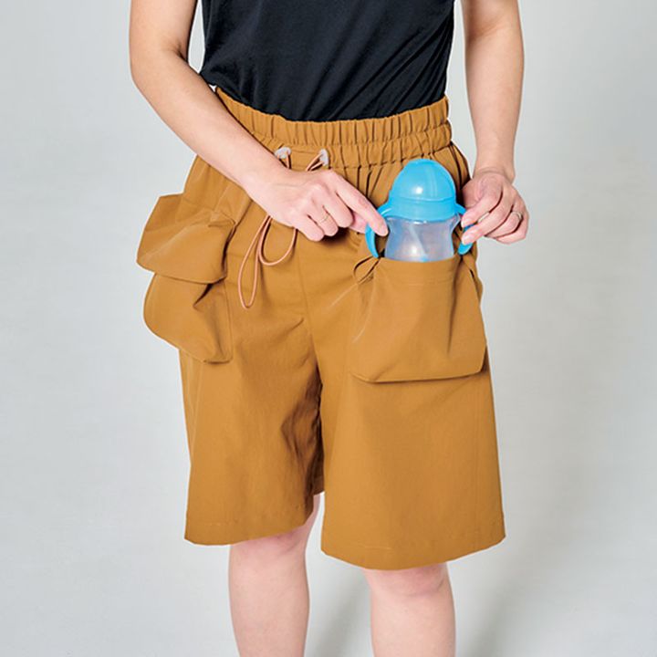 ショートパンツのポケットに水ボトルを入れるライター