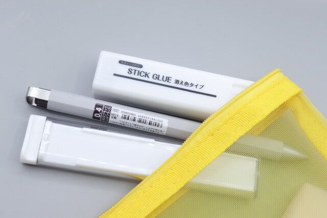 ダイソーの四角いスティックのり（消え色タイプ、8g、2本）をポーチに入れる様子