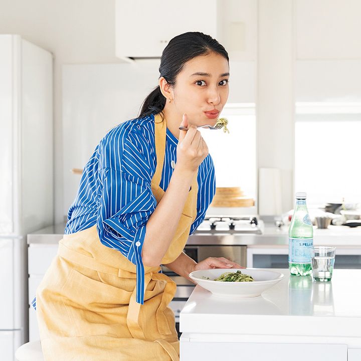 エプロン姿でパスタを口元に運んでいる武井咲さん
