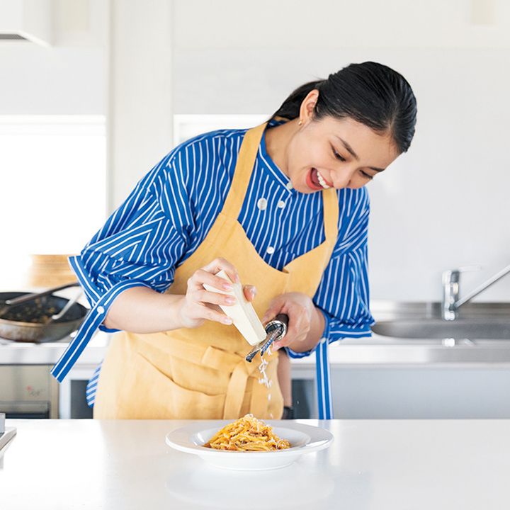 エプロン姿の武井咲さんがキッチンでカルボナーラを仕上げているところ