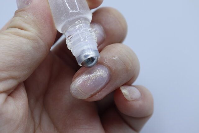 ダイソーのコロンローラーステンレスボール（約10ml）に入れたネイルオイルを指先に塗る様子