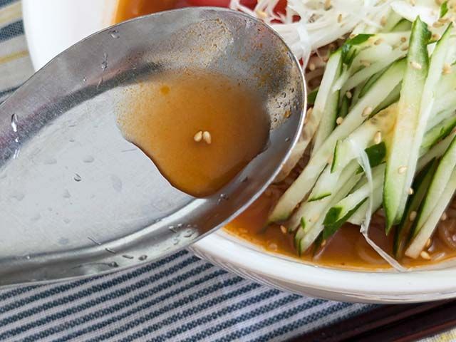 業務スーパー「トマト冷麺」のスープをレンゲですくってい様子