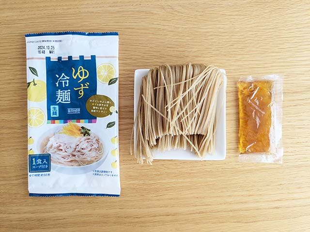 業務スーパー「ゆず冷麺」の袋の中に入っている乾麺と別添えスープがテーブルに並んでいる様子