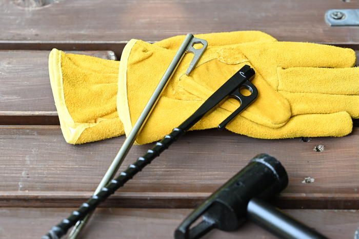 木製のテーブルの上に置かれたワークマンのチタン製ペグと電動ドライバー対応スクリューペグ