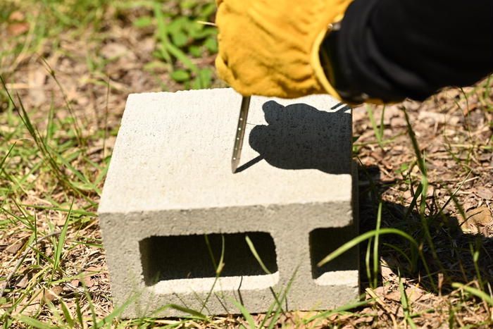 コンクリートブロックにワークマンチタン合金ペグを打ち込んでいる様子