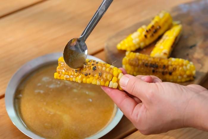 トウモロコシにクミンベースのタレを塗る様子