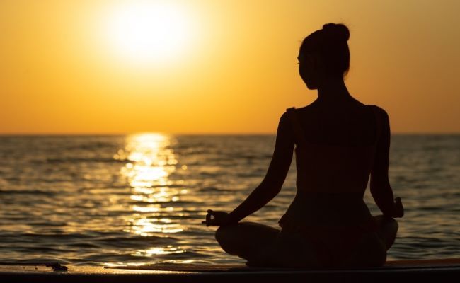 海沿いでヨガのポーズをする女性