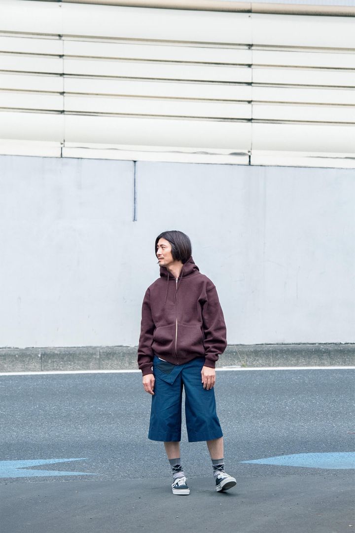 〈ベースメント ギア〉のパーカ、〈（ボッテガ・ヴェネタ〉のパンツ、〈ヴァンズ〉のスニーカー