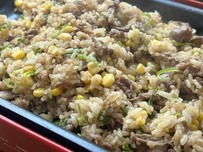 できあがったガーリックペッパーライスが赤いホットプレートに盛り付けられているところ