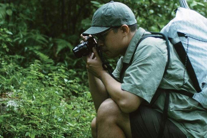 PROJ.MT.の服を着て山で撮影をする男性