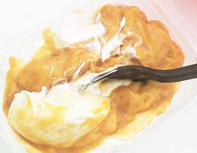 泡立てたクリームとマンゴーピューレを容器に入れ、マーブル状に混ぜ合わせている様子