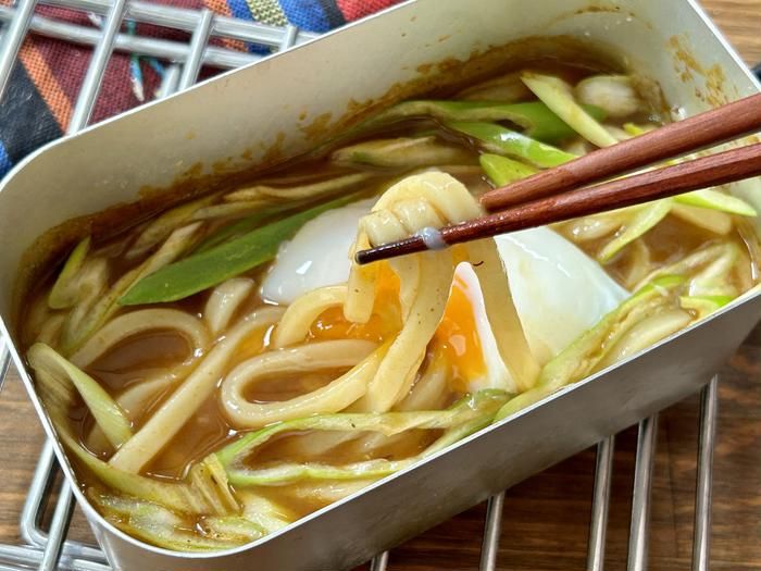 メスティンに入ったレトルトカレーで作ったカレーうどんを箸で持ち上げているところ