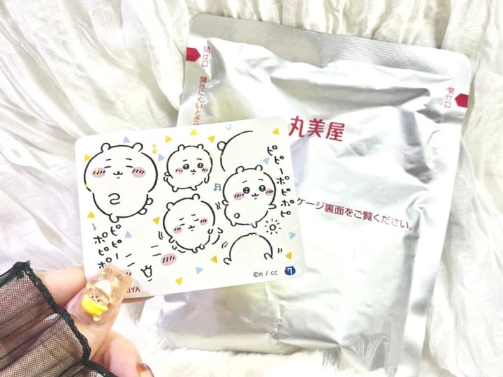 「期間限定 ちいかわ鬼辛カレー＜ビーフ＞」のレトルトカレーの袋を机に置き、スペシャルキラキラシールを手に持って紹介する画像