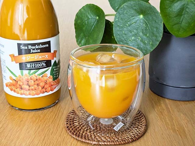 業務スーパー「サジージュース」の瓶と、コップに入った水で割ったサジージュースがテーブルに置かれている様子