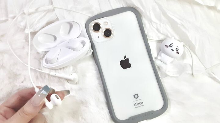 iPhoneとイヤホン、Bluetoothイヤホン、ちいかわミニフィギュアを机に置き、イヤホンの先端を手に持っている画像