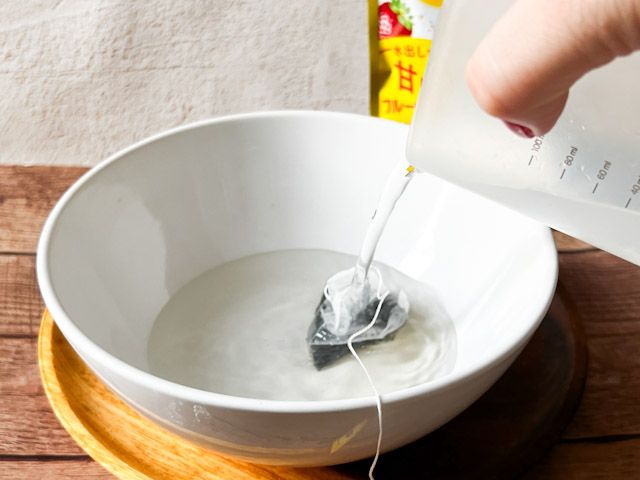 器にティーバッグを入れて水を注ぐ様子