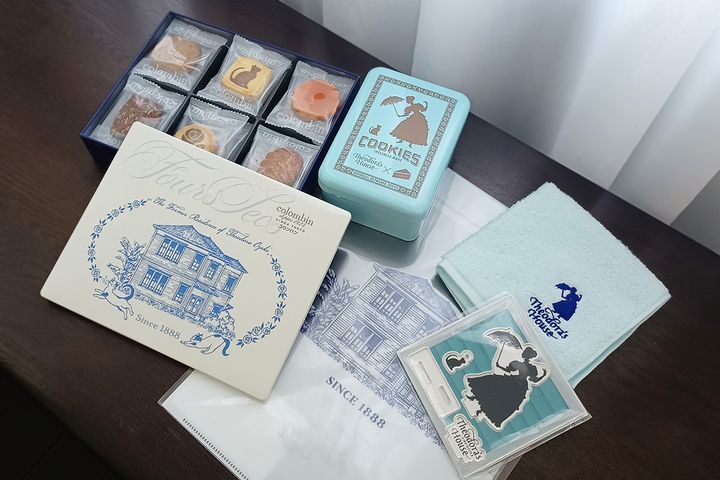 （写真左から）「旧尾崎テオドラ邸オリジナルクッキー缶」2200円、「コラボクッキー缶」3500円、「旧尾崎テオドラ邸オリジナルクリアファイル」550円、「旧尾崎テオドラ邸オリジナル刺繍ハンカチ（ブルー）」1320円、「旧尾崎テオドラ邸オリジナルアクスタ＆アクキーセット」1540円
