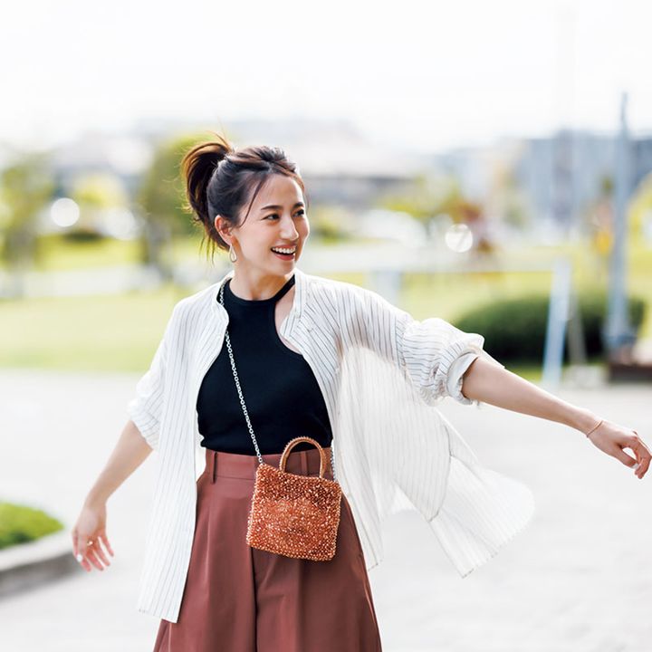 ストライプ柄のシアーシャツのインナーにアシメントリーの黒タンクを重ねてボトムスにカラーパンツを合わせた東原亜希さん