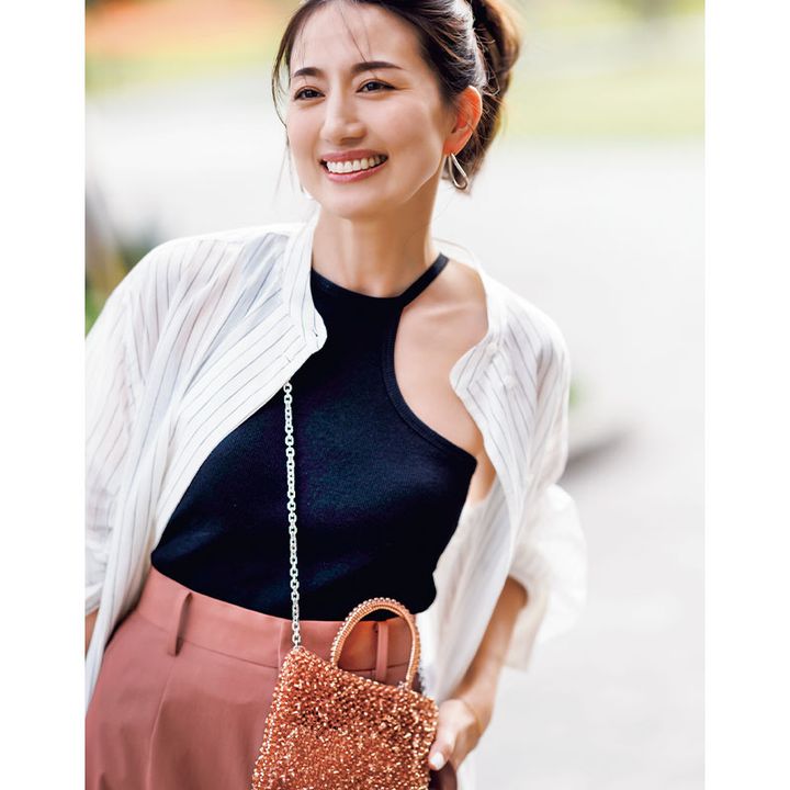 ストライプ柄のシアーシャツのインナーにアシメントリーの黒タンクを重ねてボトムスにカラーパンツを合わせた東原亜希さん