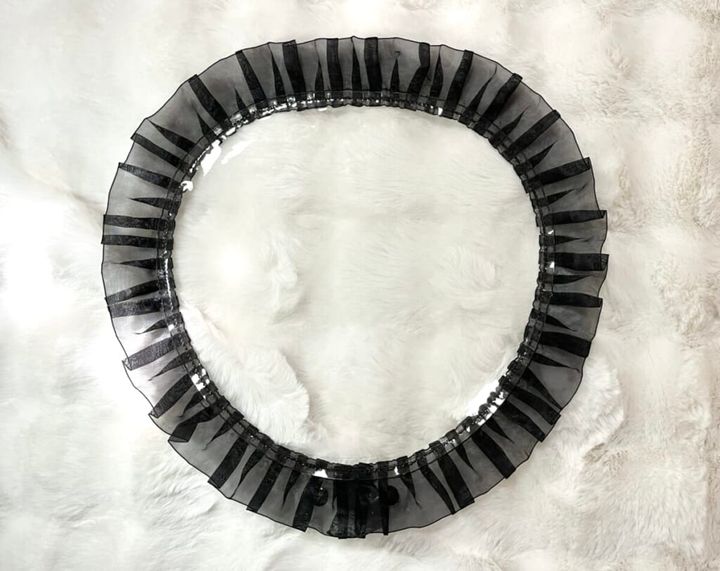 3COINS（スリーコインズ）の「フリルうちわカバー」をカーペットの上に置いて紹介する画像