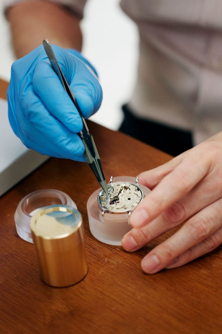 ピンセットで腕時計を組み立てる様子