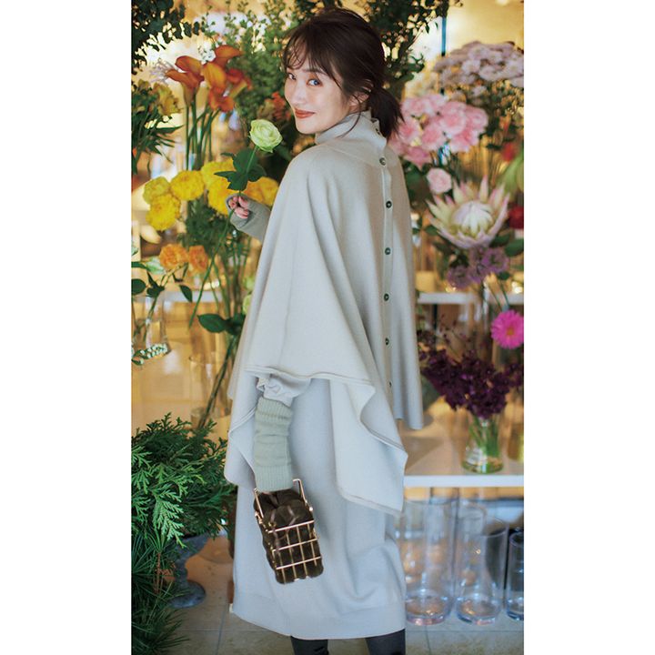 フラワーショップのなかで花を持って振り向く高梨臨さんの写真