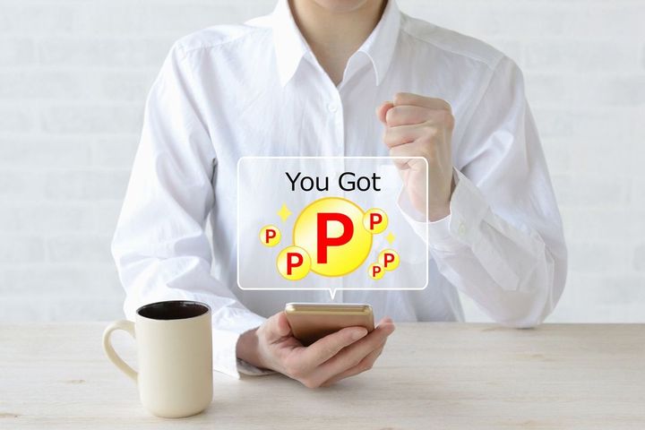 ポイントを獲得したことを知らせるスマホの画面にガッツポーズをする女性