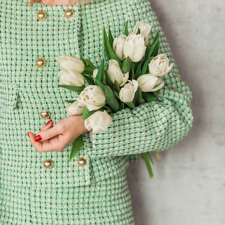 グリーンのツイードスーツを着て花束を抱えた女性