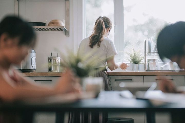 母親が皿を洗っている間ダイニングルームで勉強している子供たち