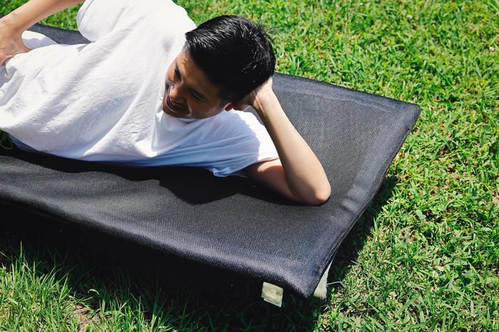 エスカルゴマットをコットに敷いて寝ている男性