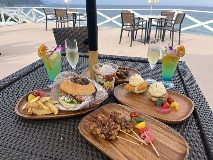 手前「牛肉のサテー」2200円、中央右「シェルサンドウィッチ」2500円、中央左「かもめバーガー」3000円、中央「シェイクサラダ」1400円、右奥から「オリジナルカクテル」1300円、「シャンドンブリュット（グラス）」1800円